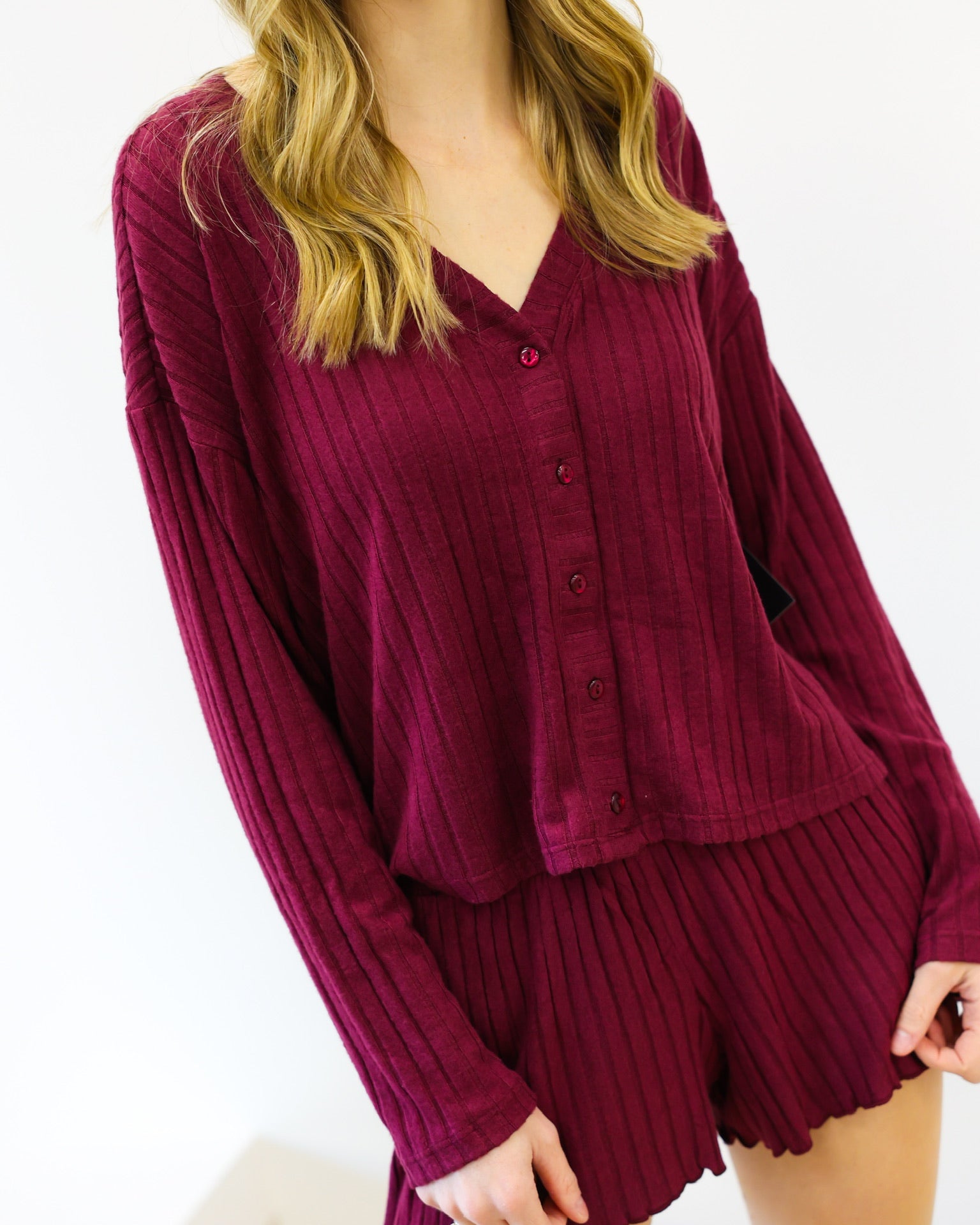 Woman wearing a burgundy ribbed lounge set on a white background