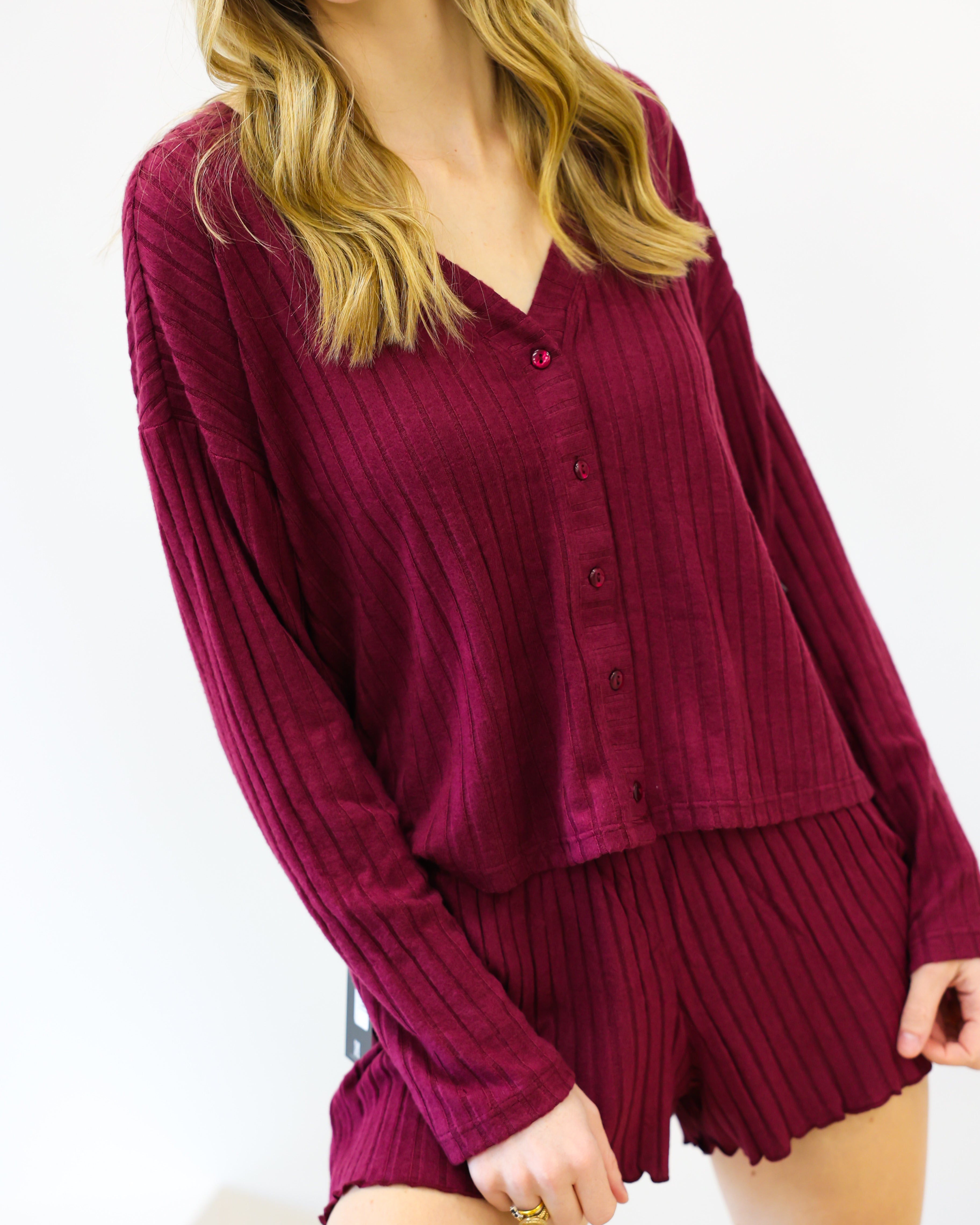 Woman wearing a burgundy ribbed lounge set on a white background