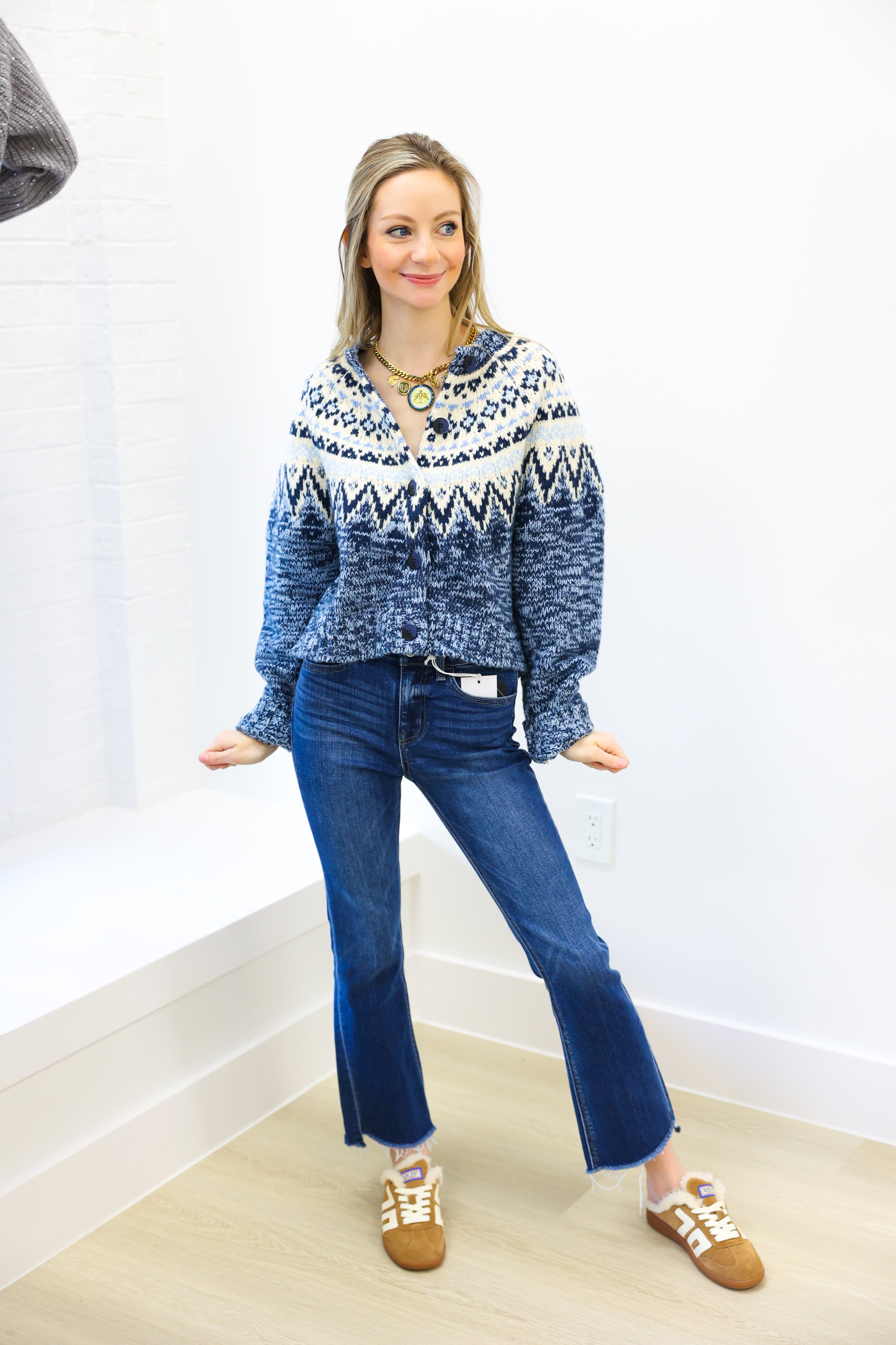 Woman wearing a blue and white patterned sweater with blue jeans indoors.