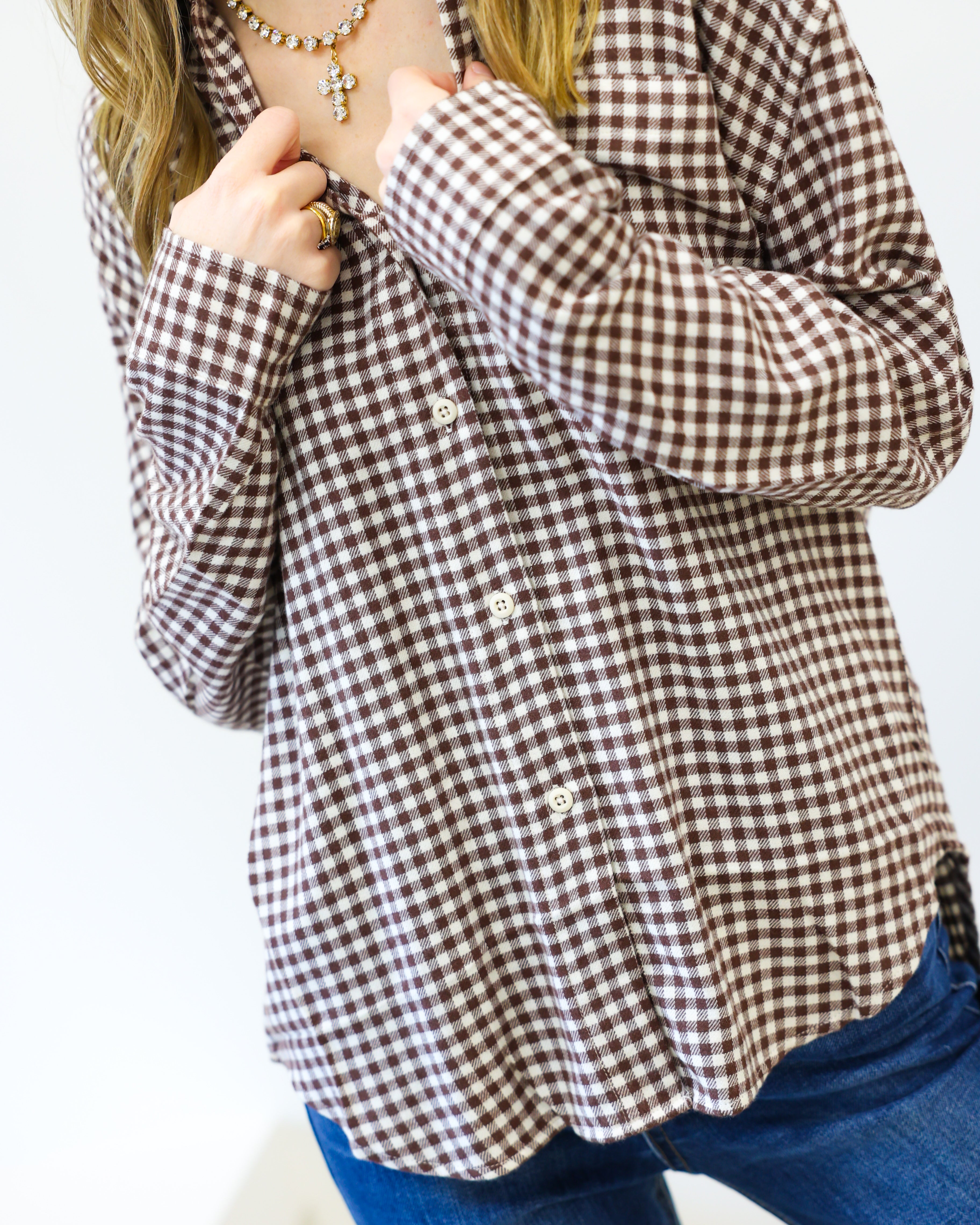 Person wearing a brown and white checkered shirt with blue jeans on a white background