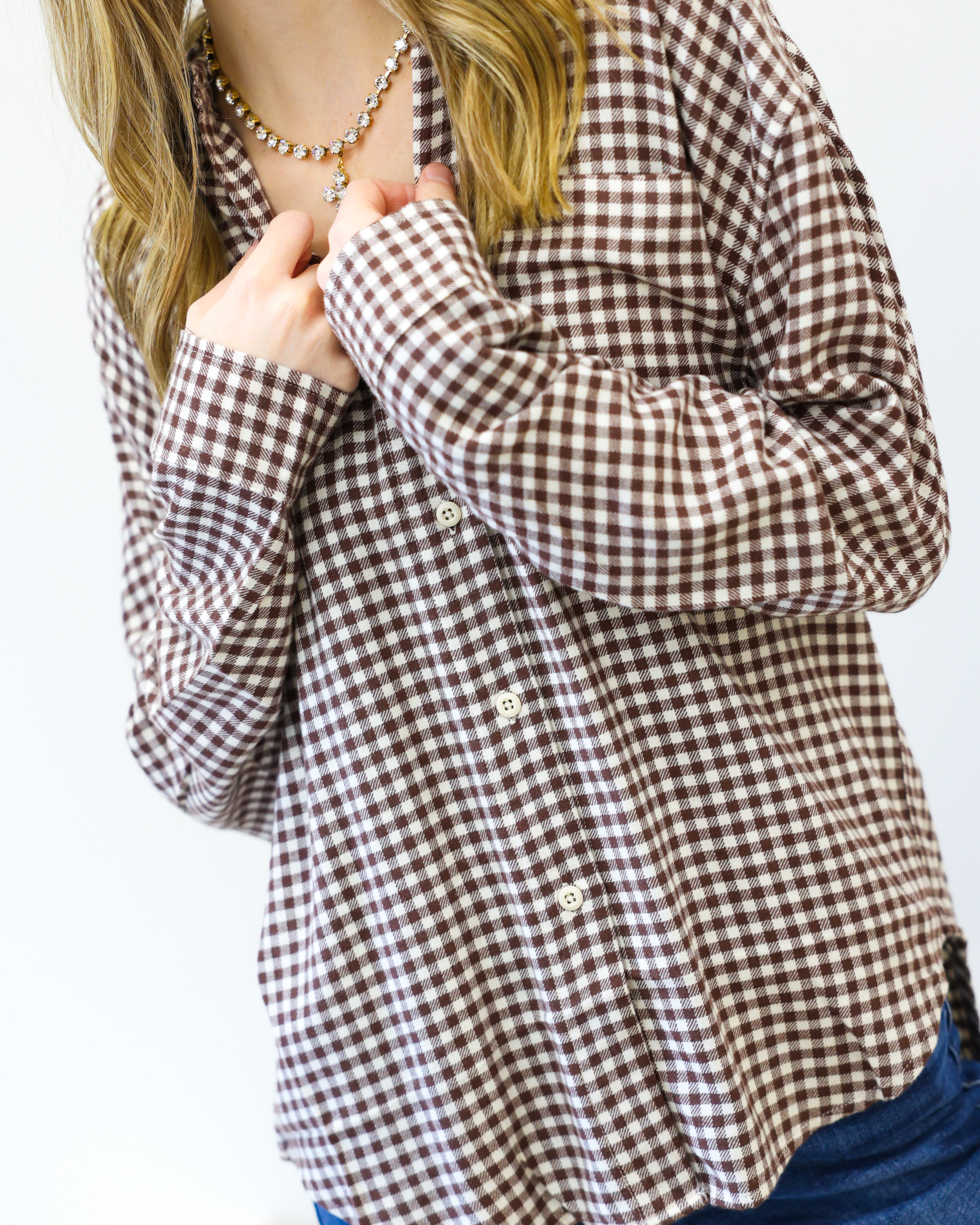 Person wearing a brown and white checkered shirt with a plain background