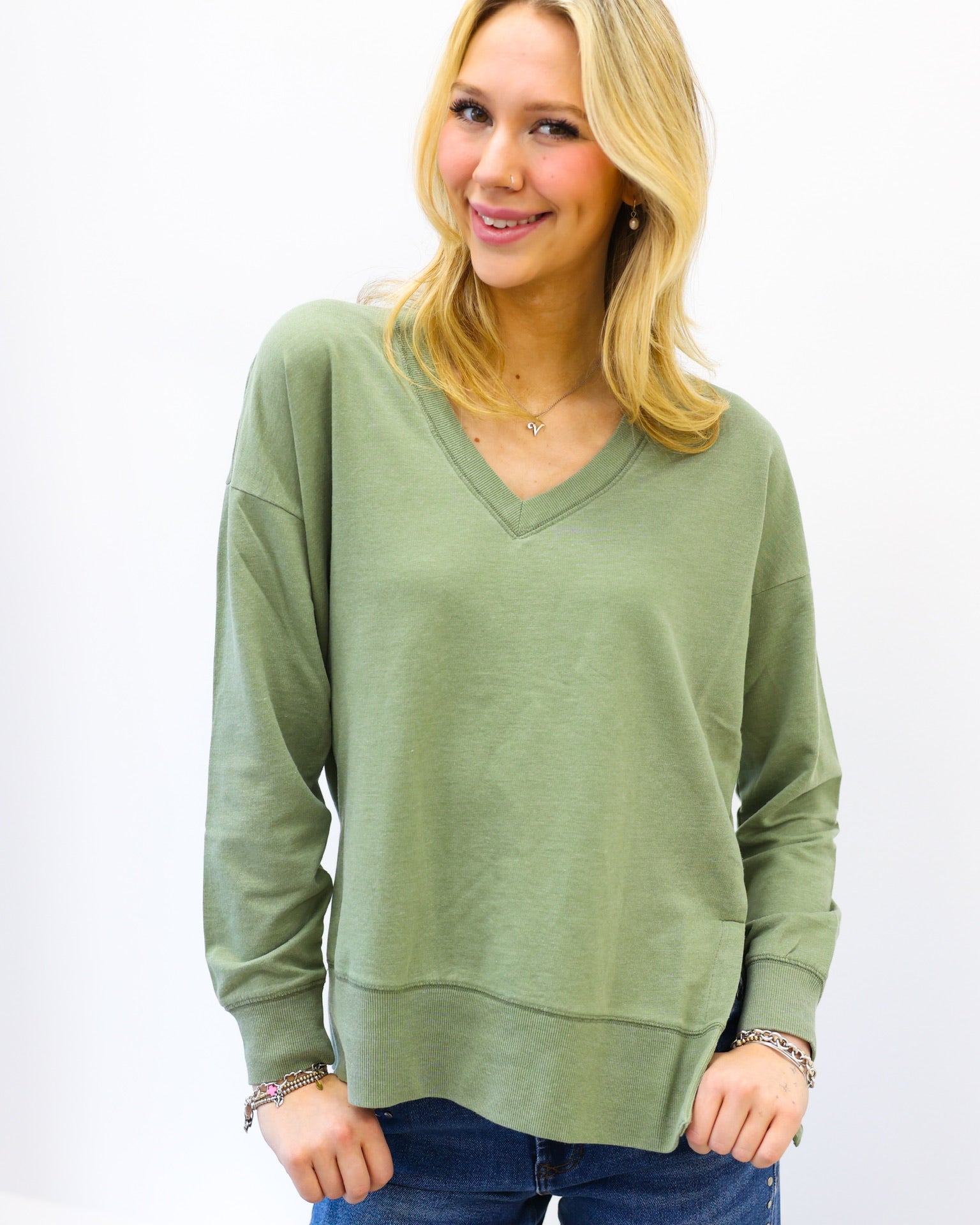 Woman wearing a green sweater and blue jeans on a white background