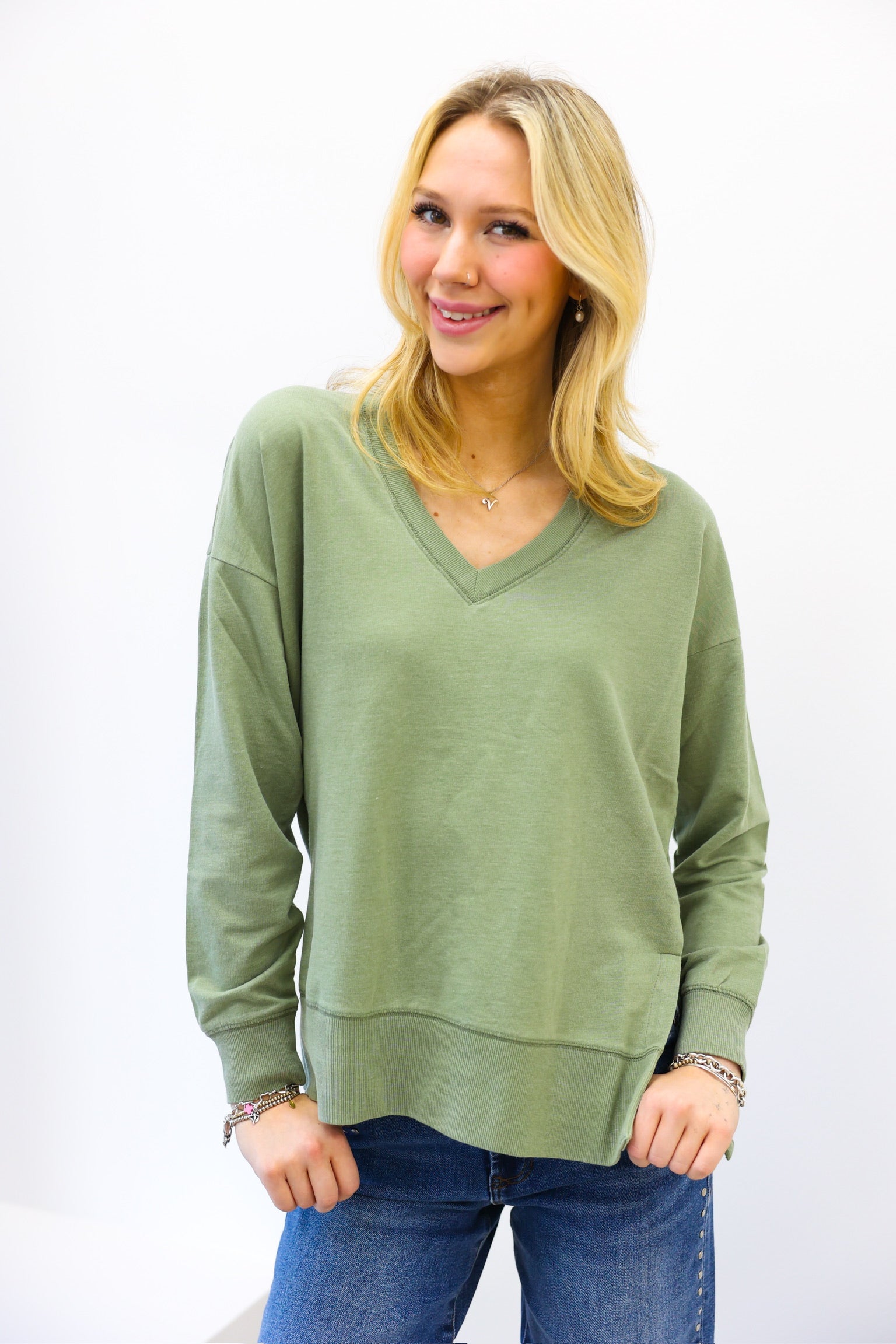 Woman wearing a green sweater and blue jeans on a white background