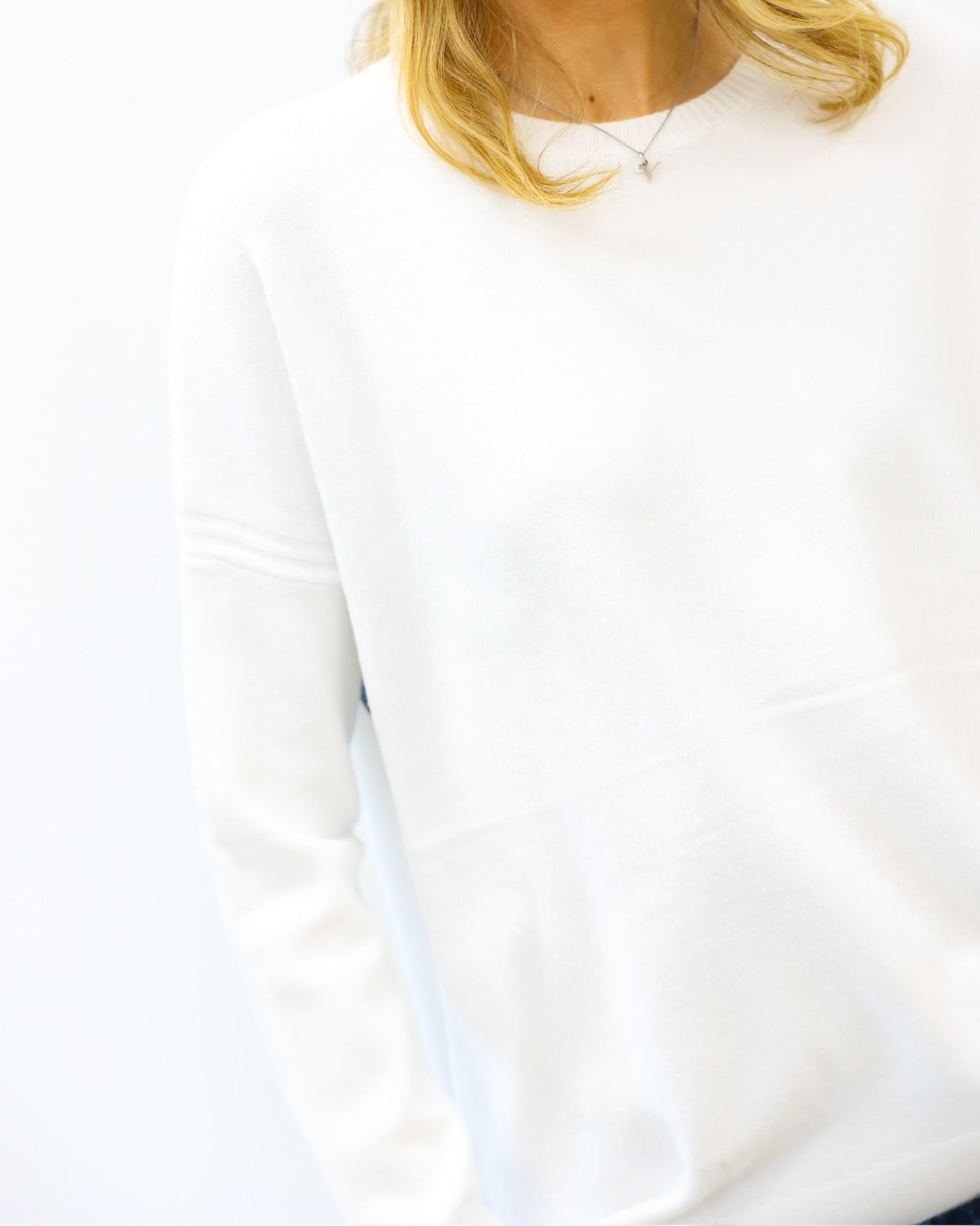 White sweatshirt worn by a person with blonde hair, on a white background