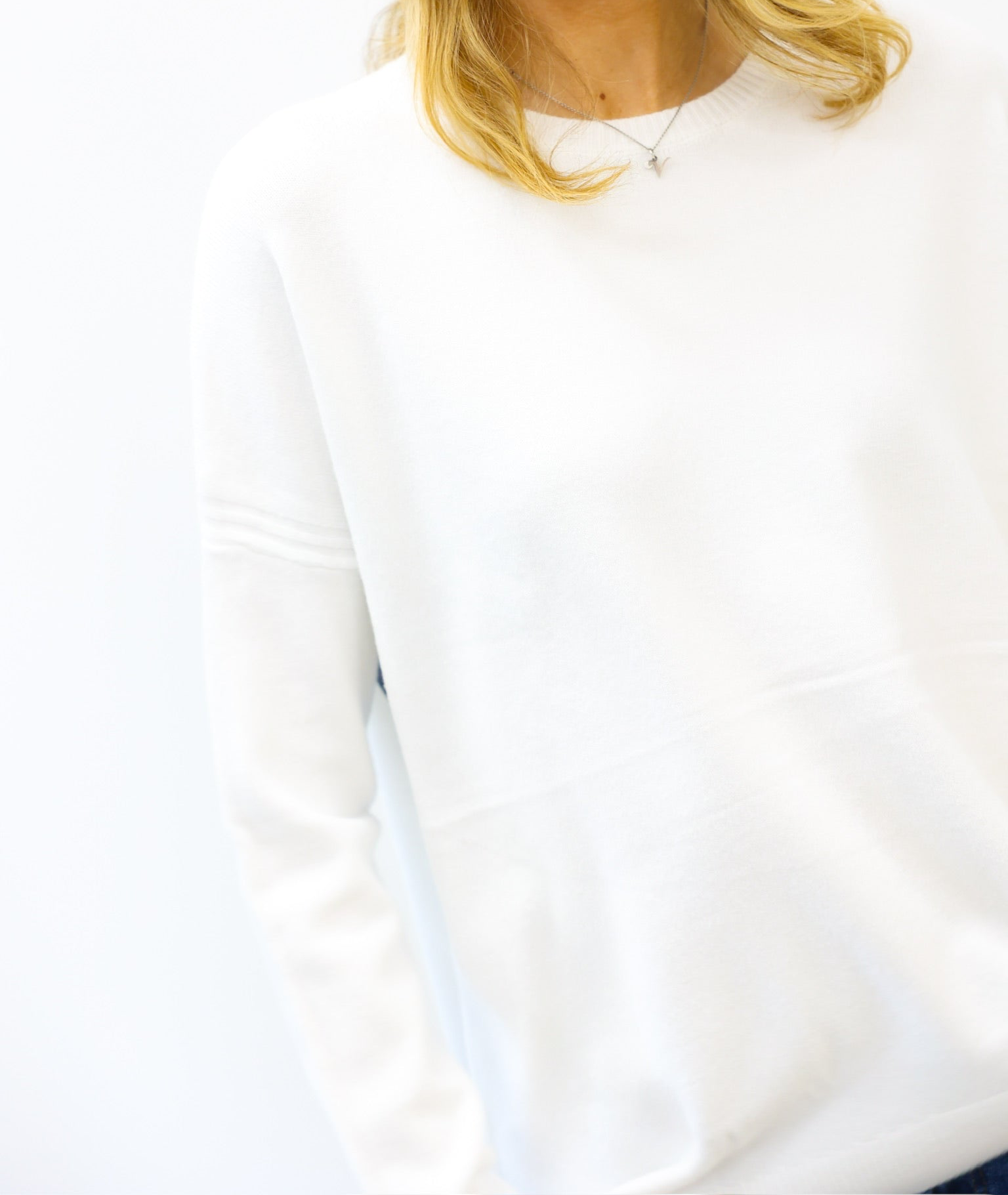 White sweatshirt worn by a person with blonde hair, on a white background