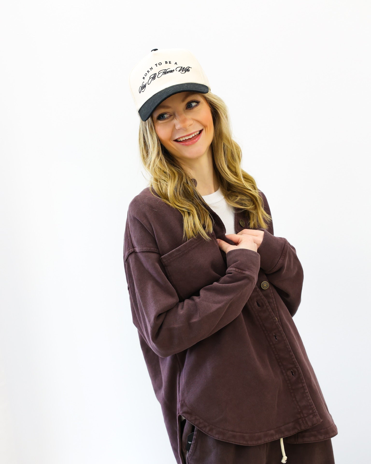Person wearing a brown jacket and cap on a white background