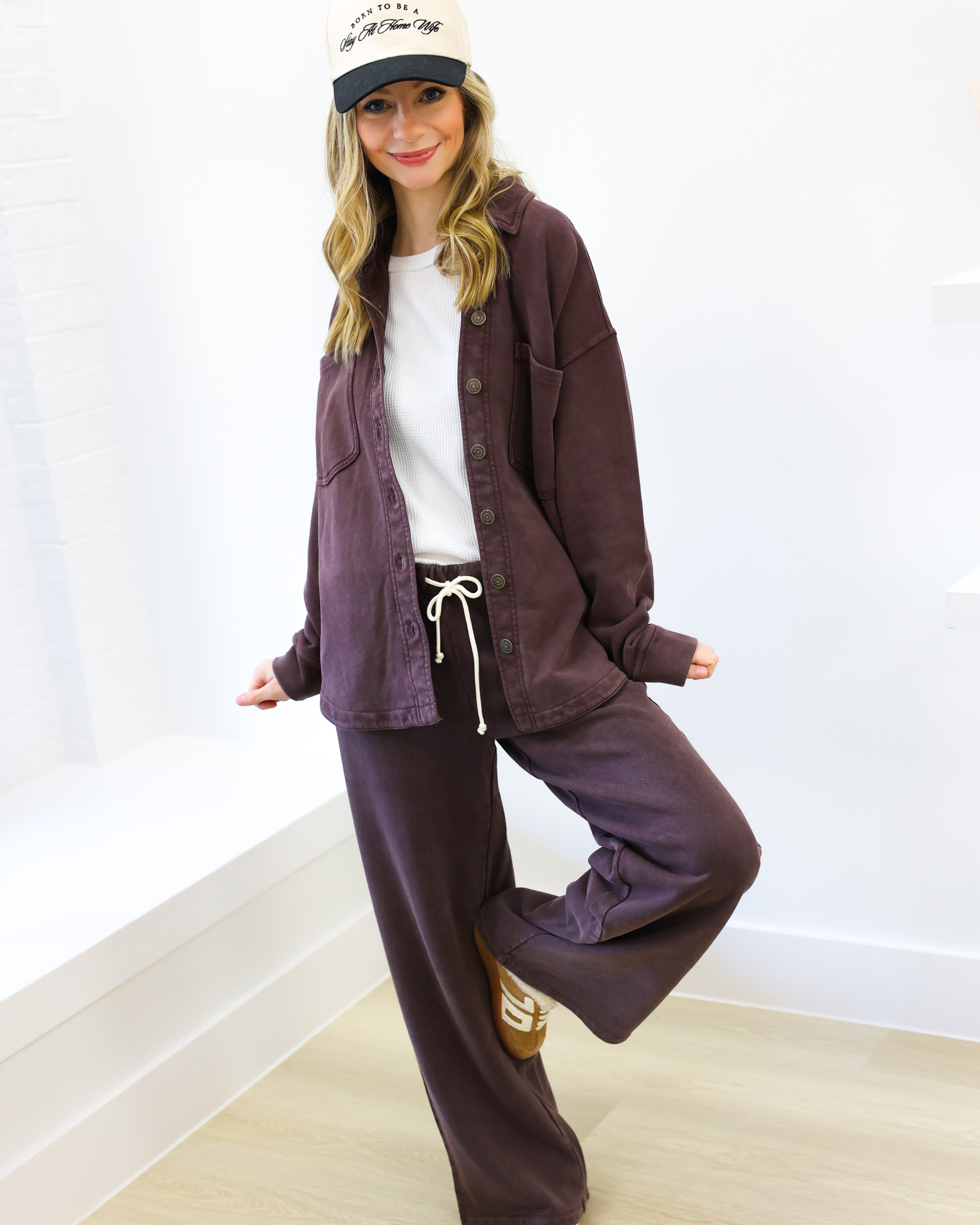 Person wearing a purple tracksuit and white cap against a white background