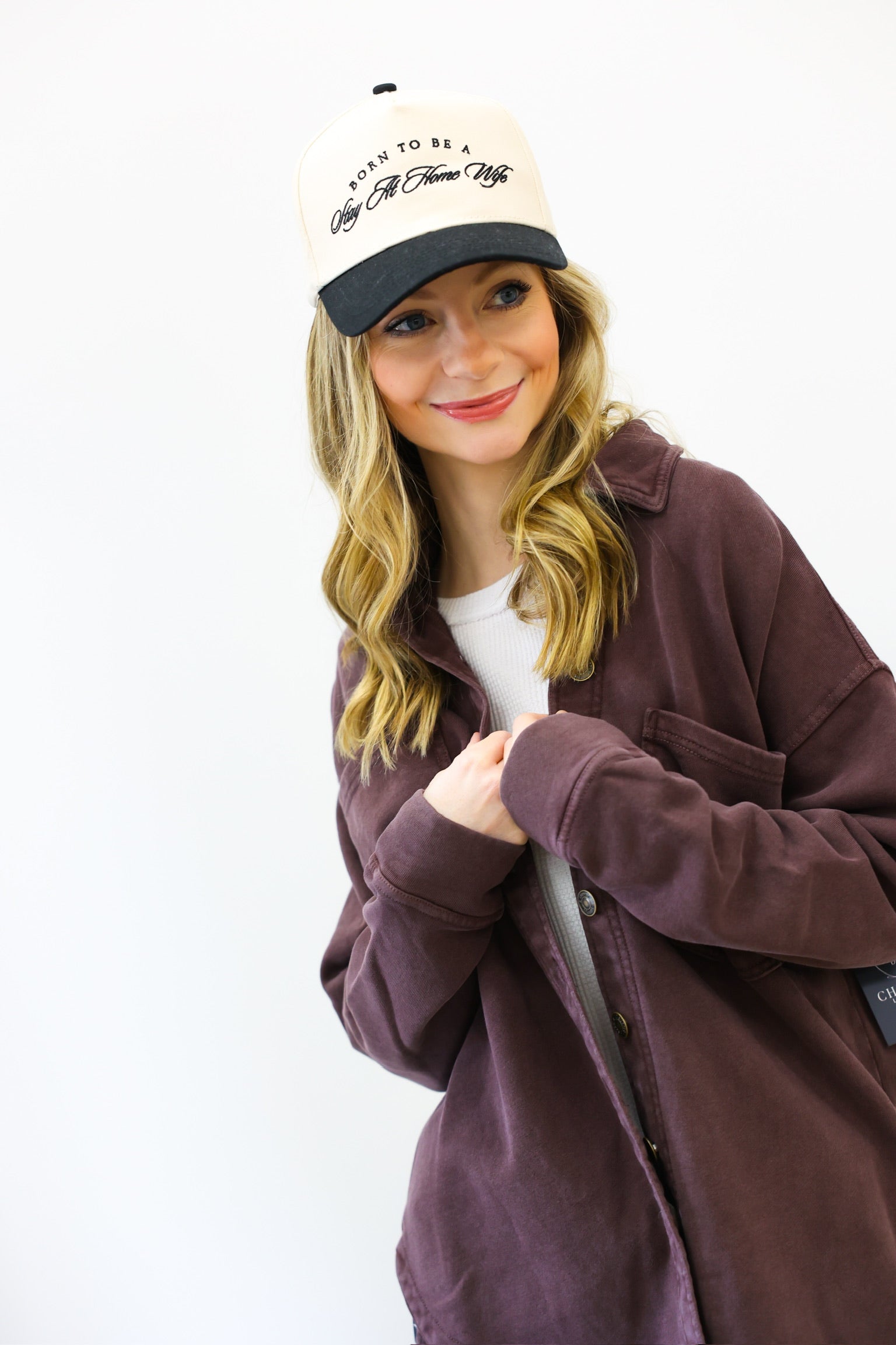 Person wearing a brown jacket and a cap with text on a white background