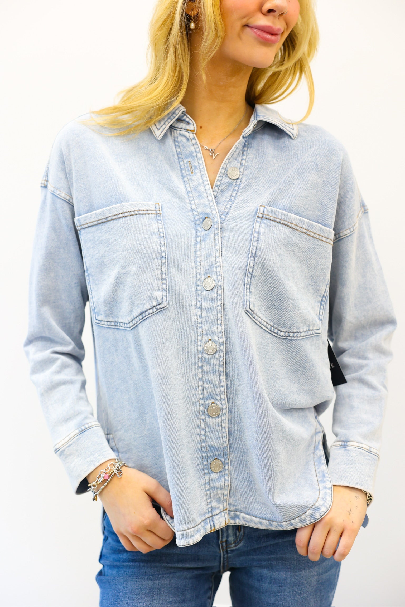 Woman wearing a light blue denim shirt with a white background