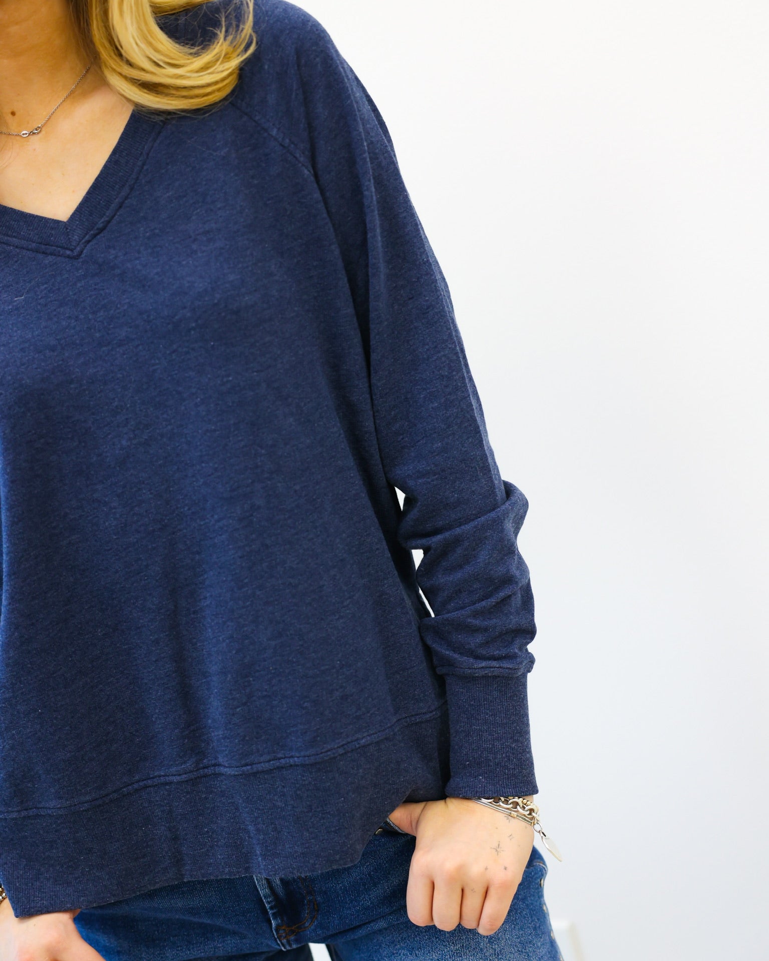 Person wearing a blue sweater and jeans on a white background