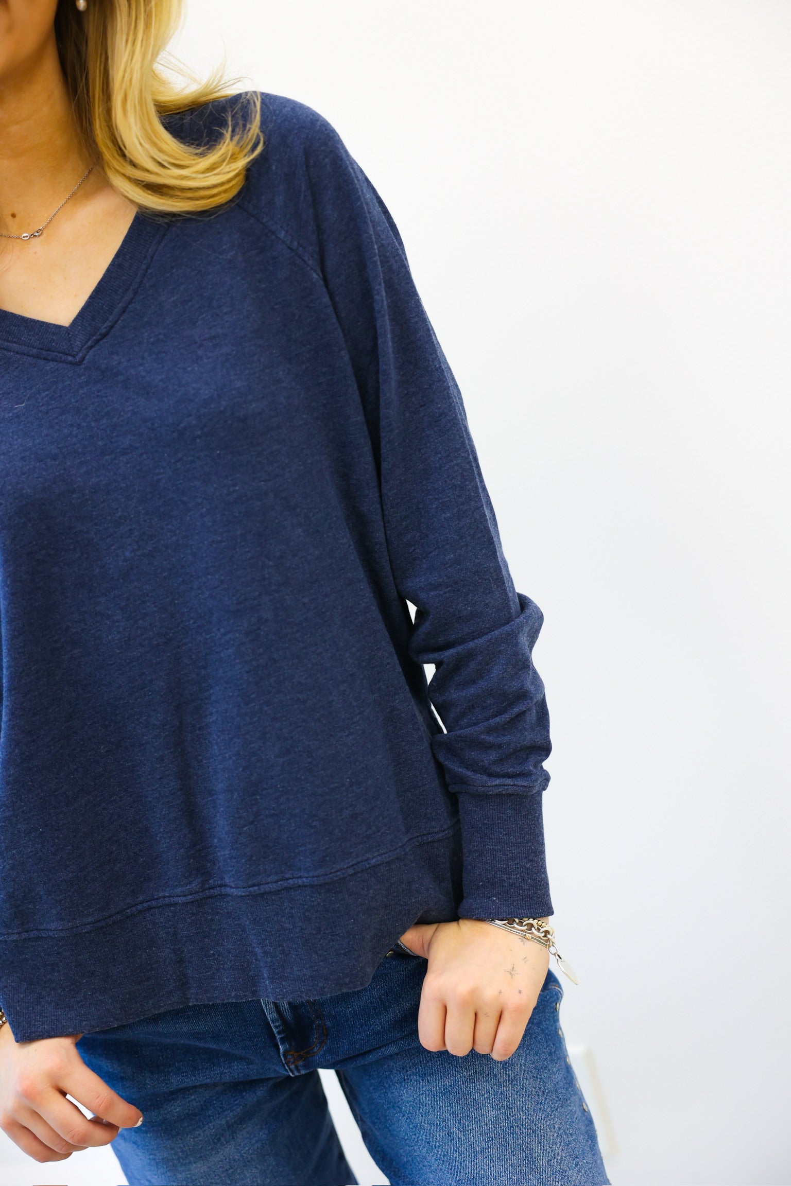 Person wearing a blue sweater and jeans on a white background