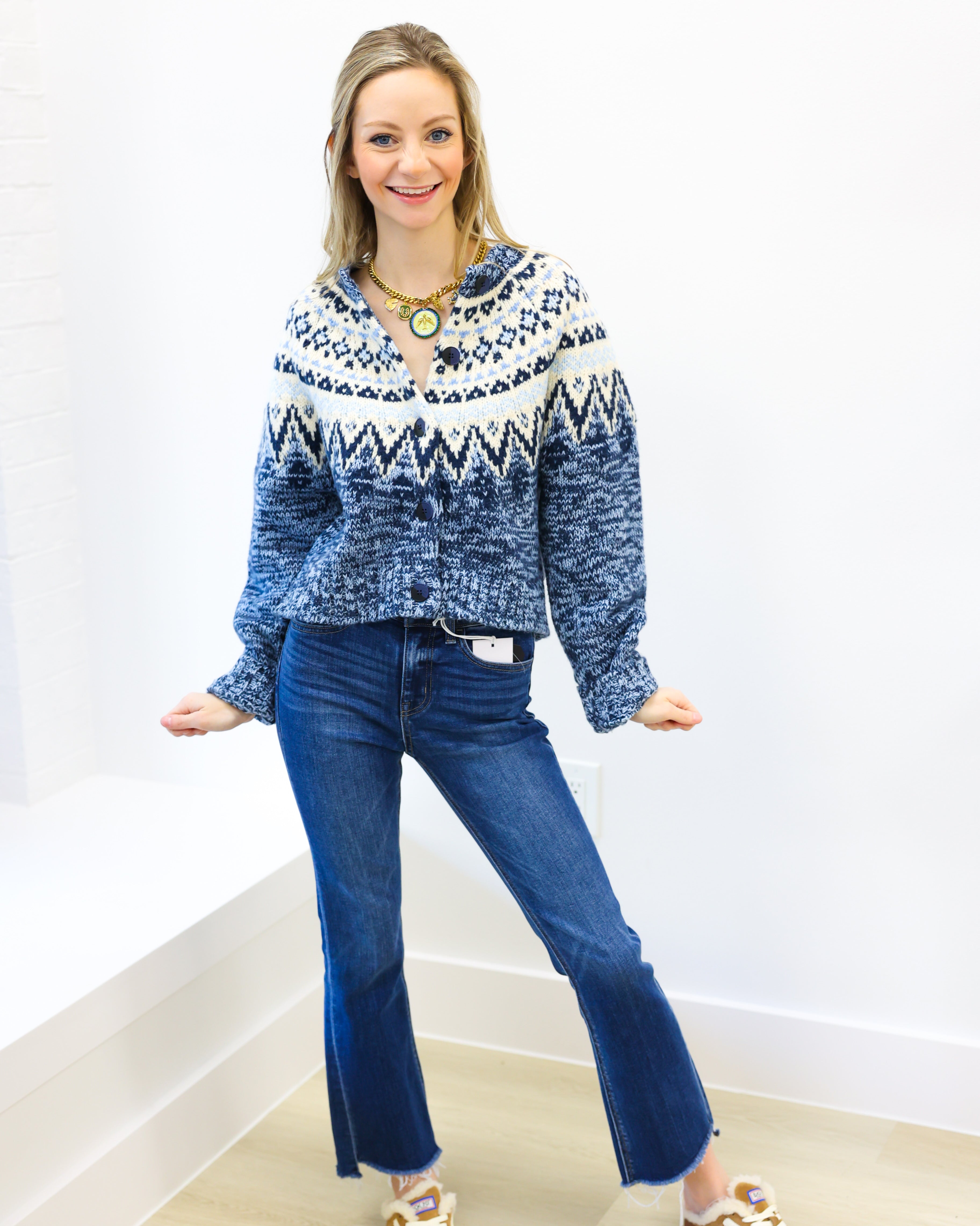 Woman wearing a blue and white patterned sweater and blue jeans on a white background