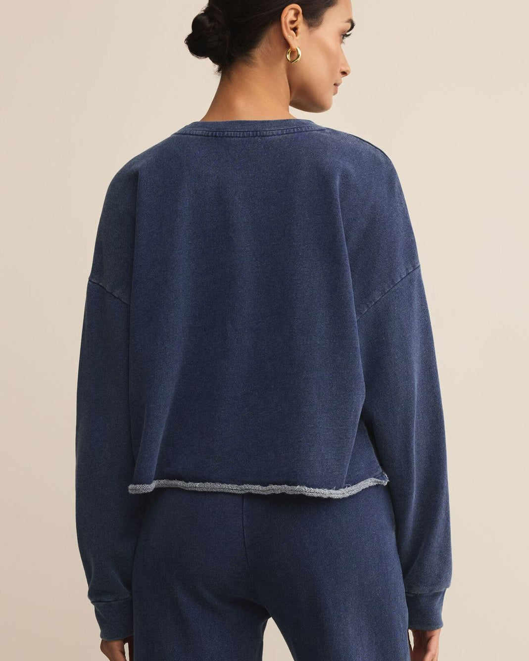 Woman wearing a navy blue sweatshirt and pants on a beige background