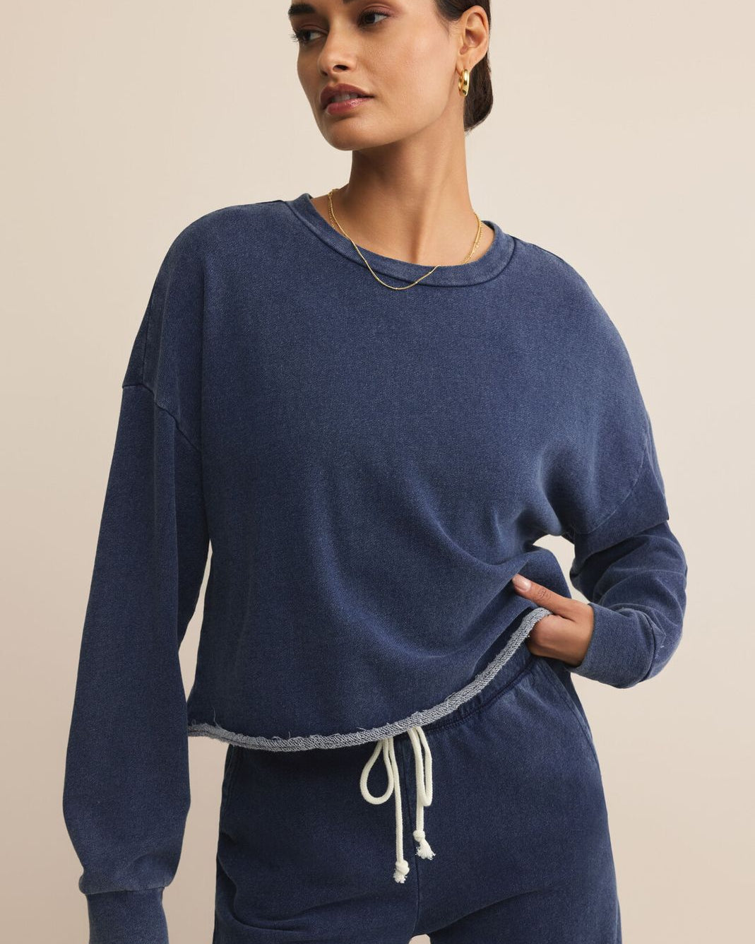 Woman wearing a blue lounge set against a beige background