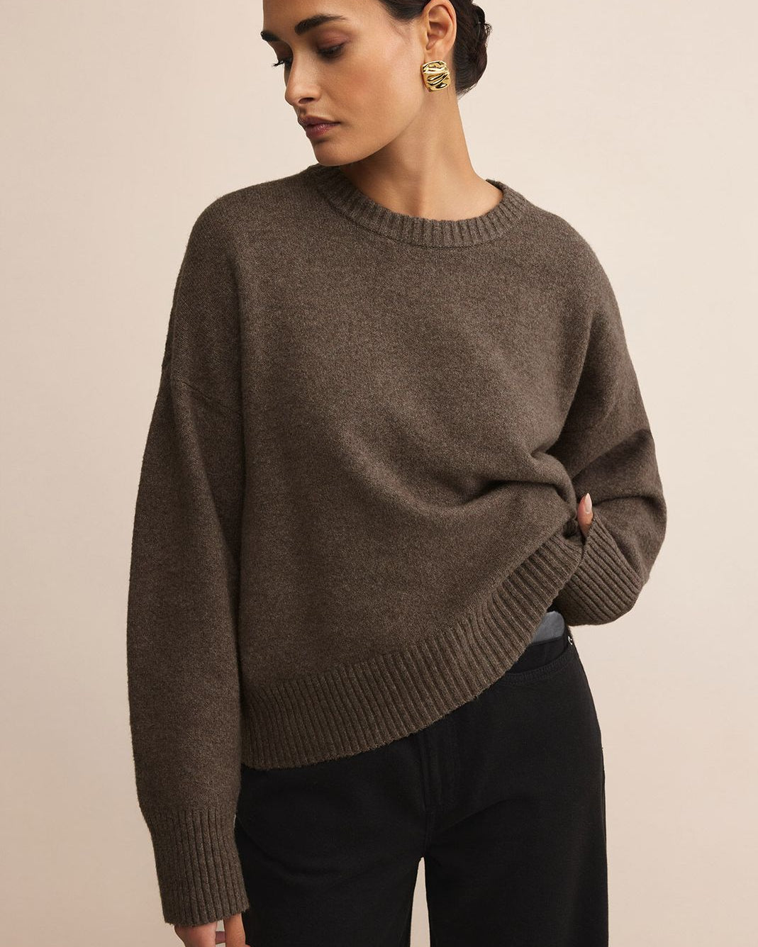 Woman wearing a brown sweater against a beige background