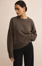 Woman wearing a brown sweater against a beige background