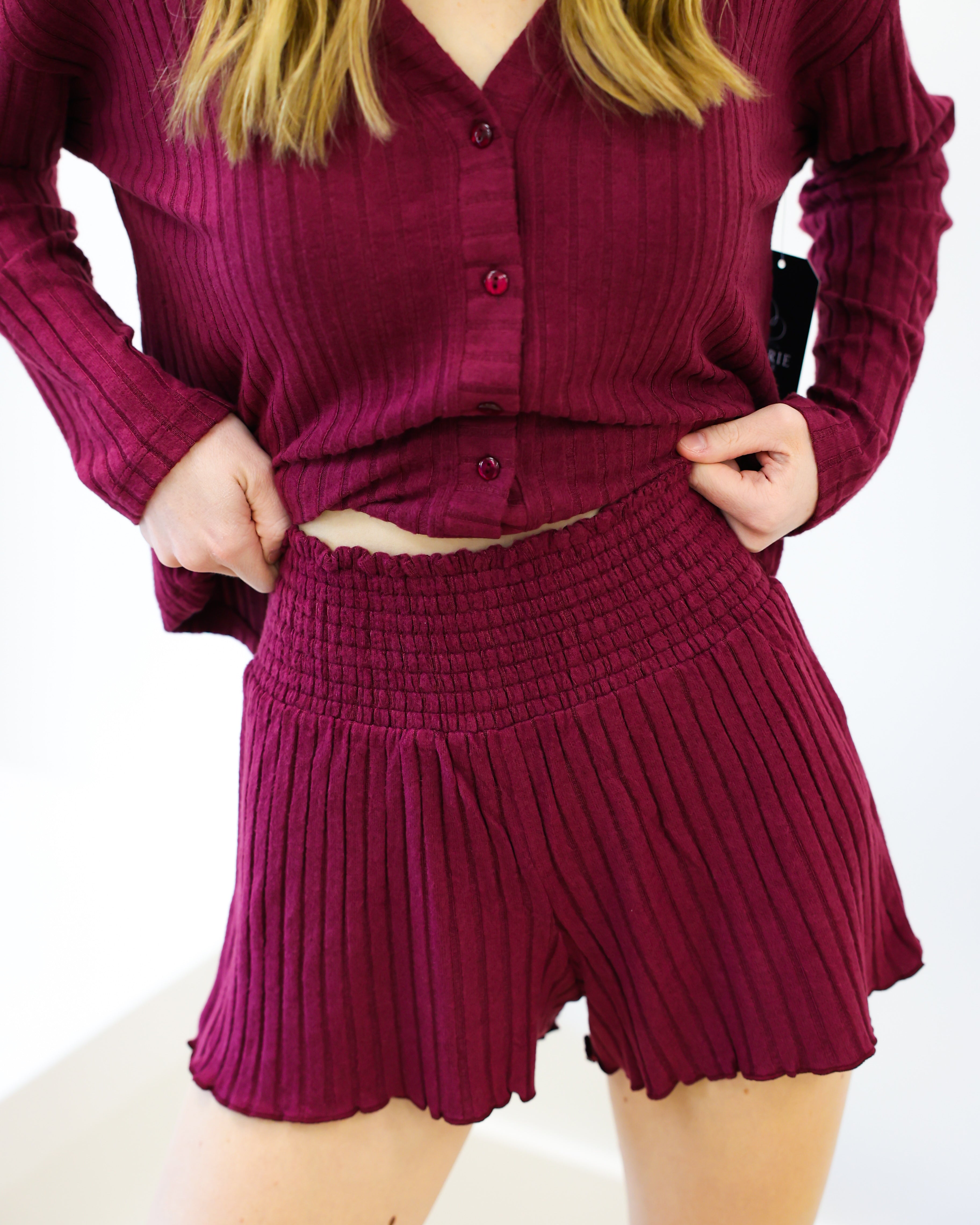 Person wearing a maroon ribbed outfit with a top and shorts on a white background