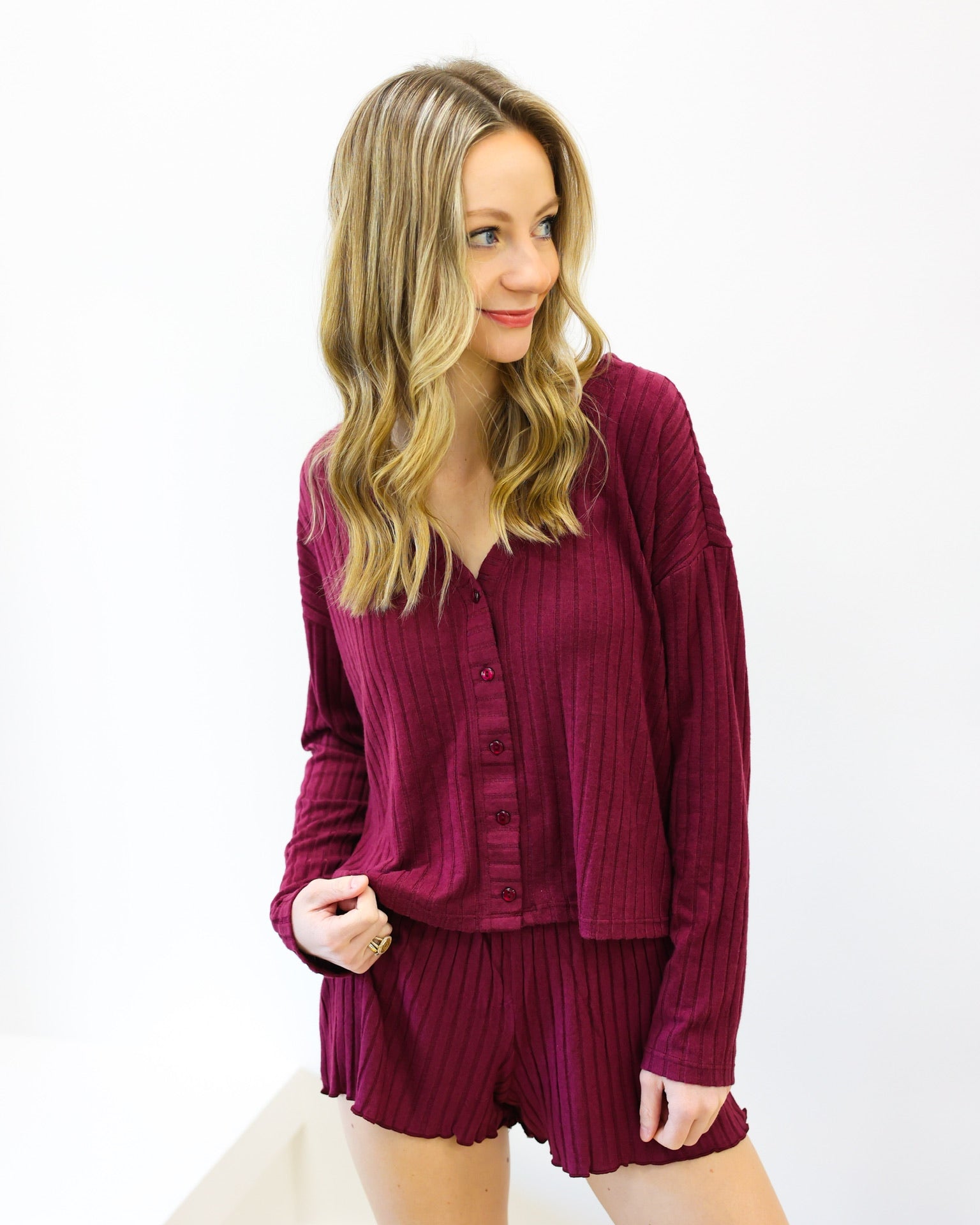 Woman wearing a burgundy outfit with a top and shorts on a white background