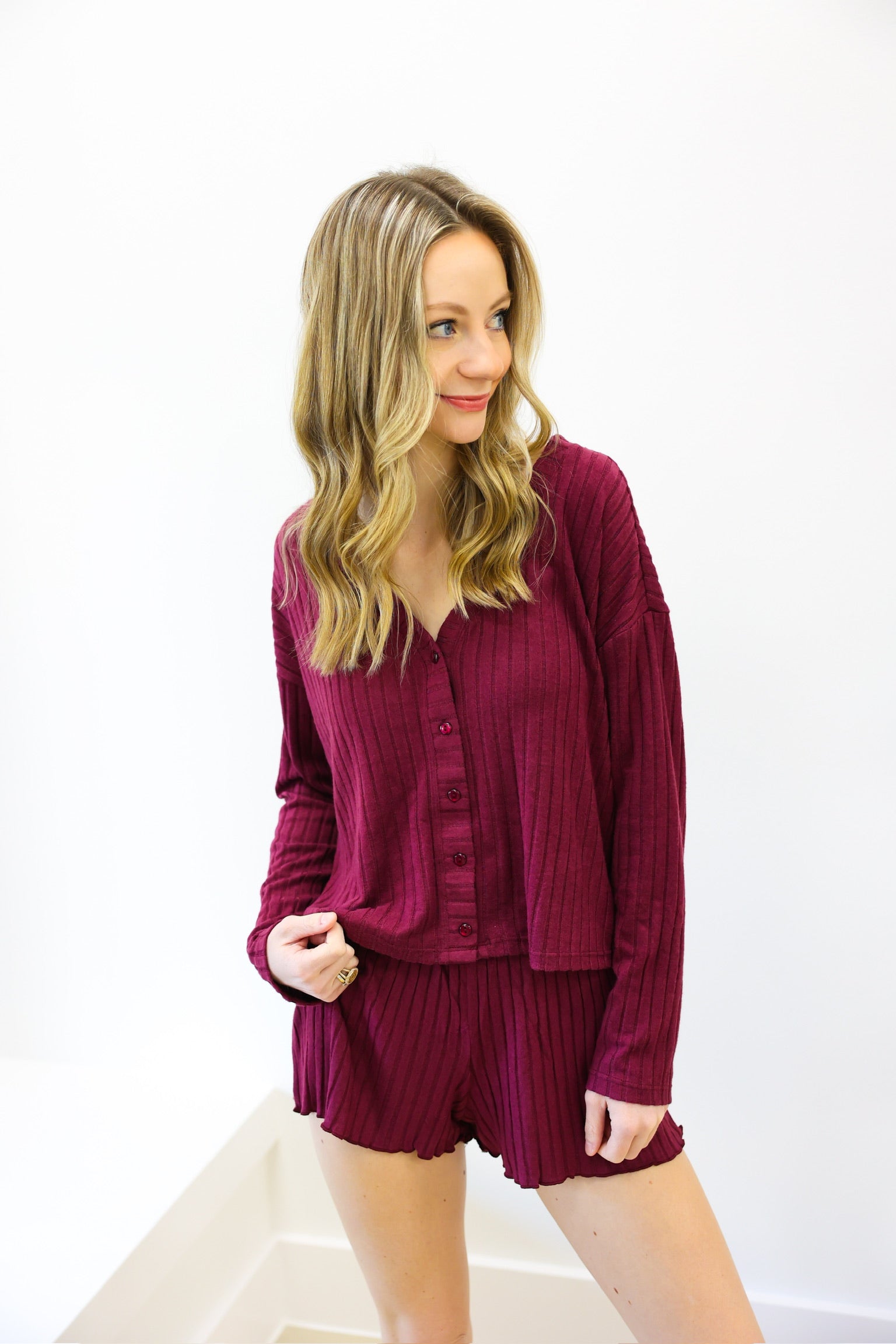 Woman wearing a burgundy outfit with a top and shorts on a white background
