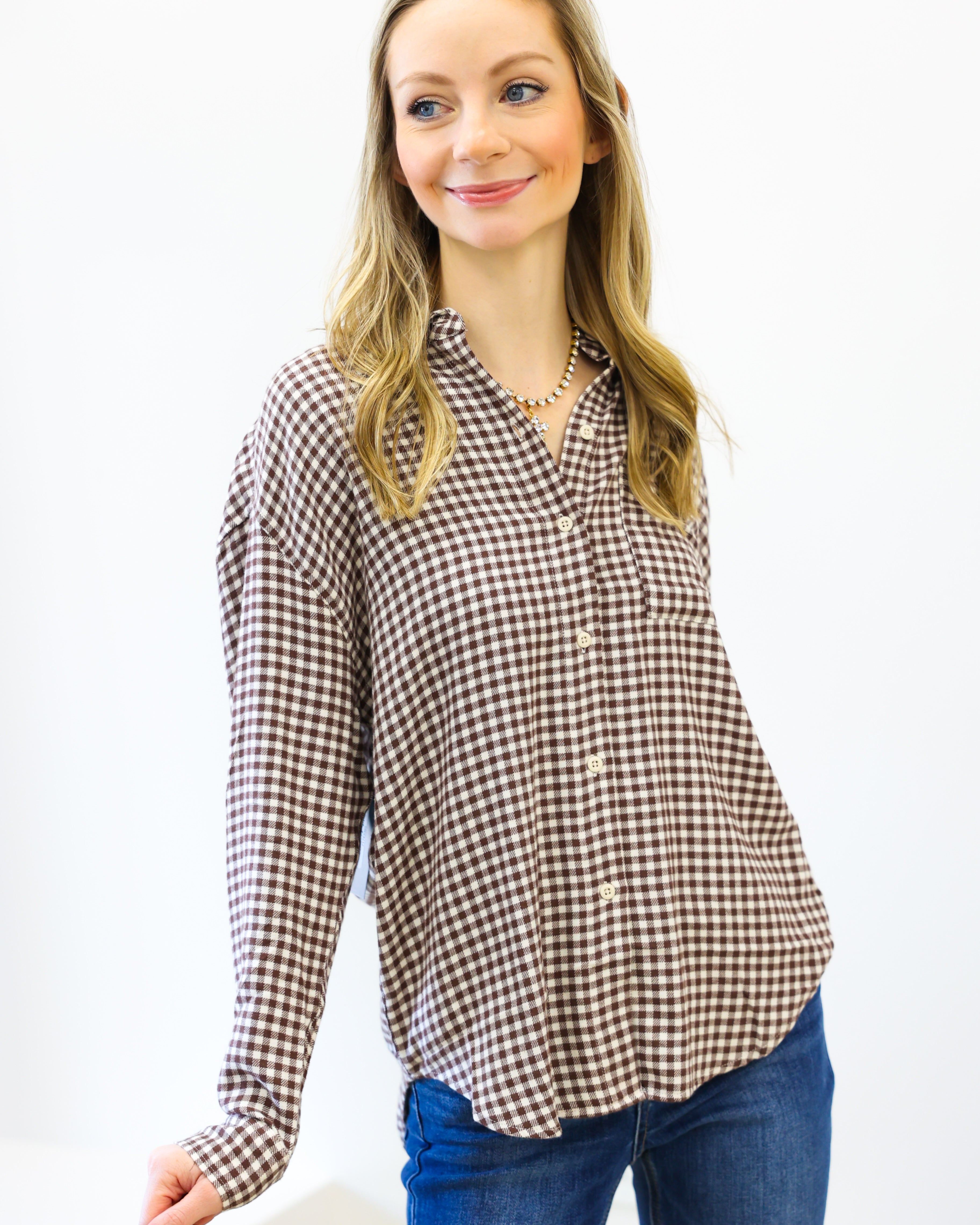Woman wearing a brown and white checkered shirt with blue jeans on a white background