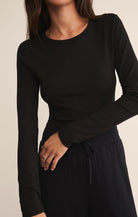Black long-sleeve top worn by a person on a beige background