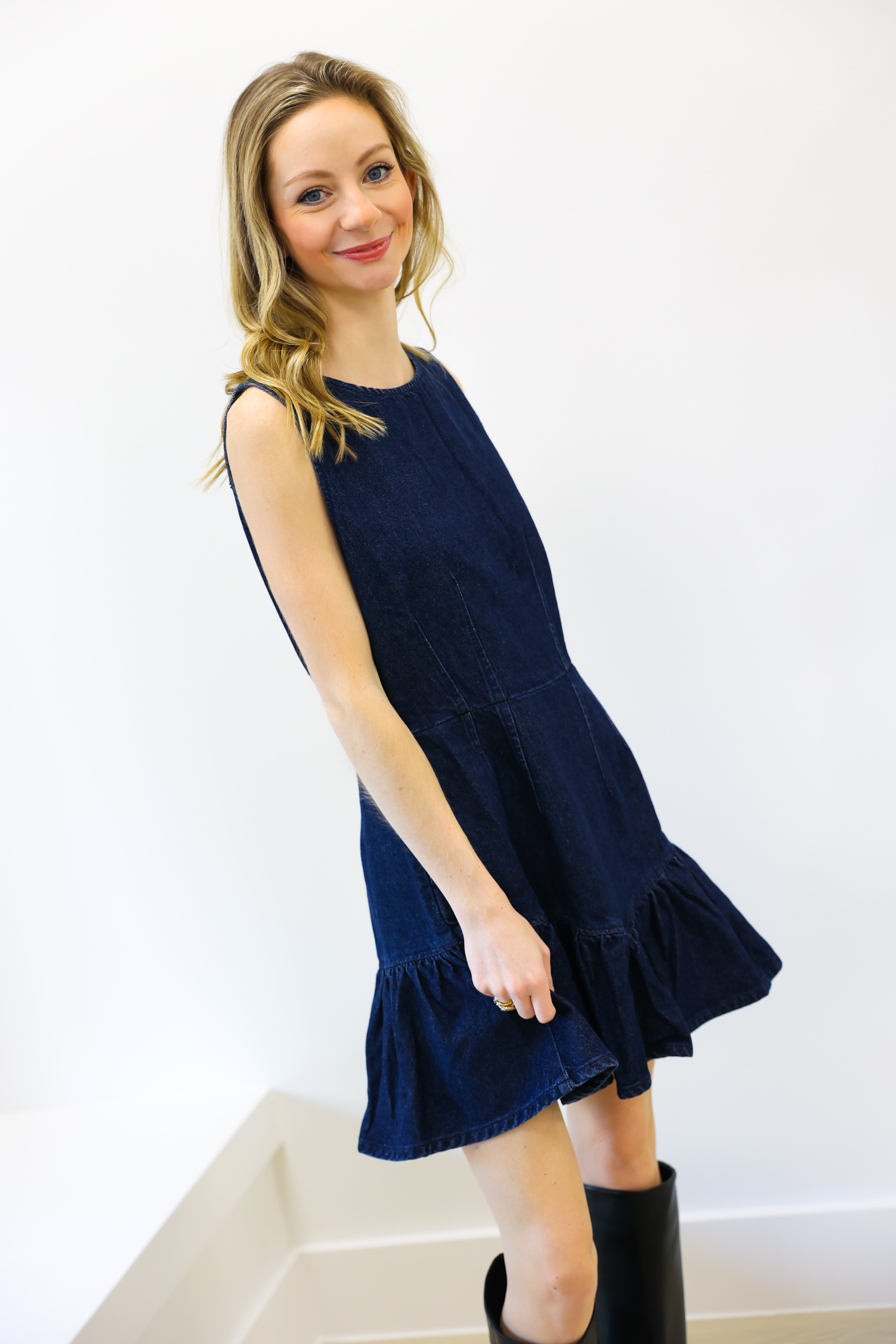 Woman wearing a navy denim blue dress with a white background