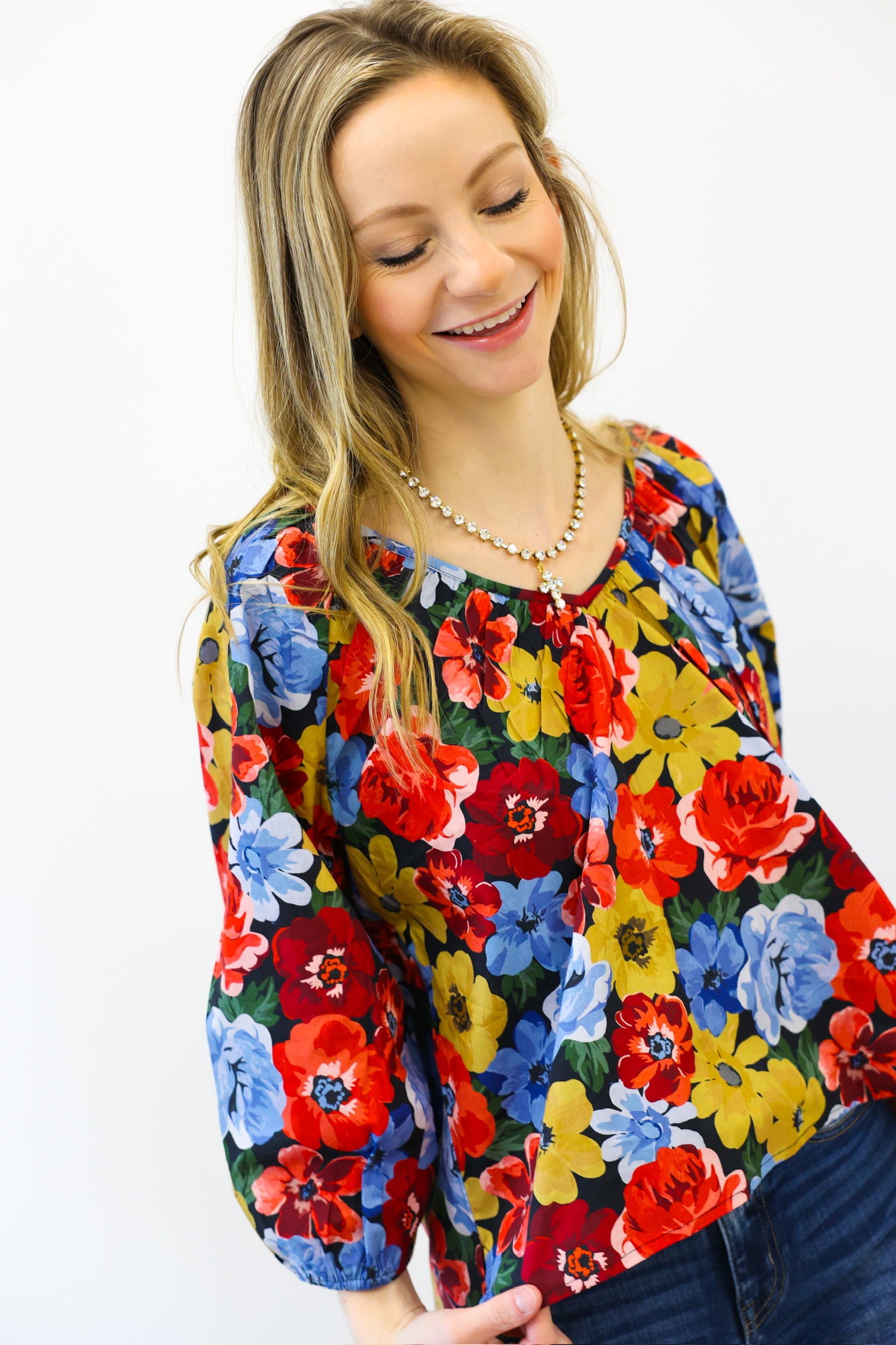 Woman wearing a colorful floral blouse against a white background