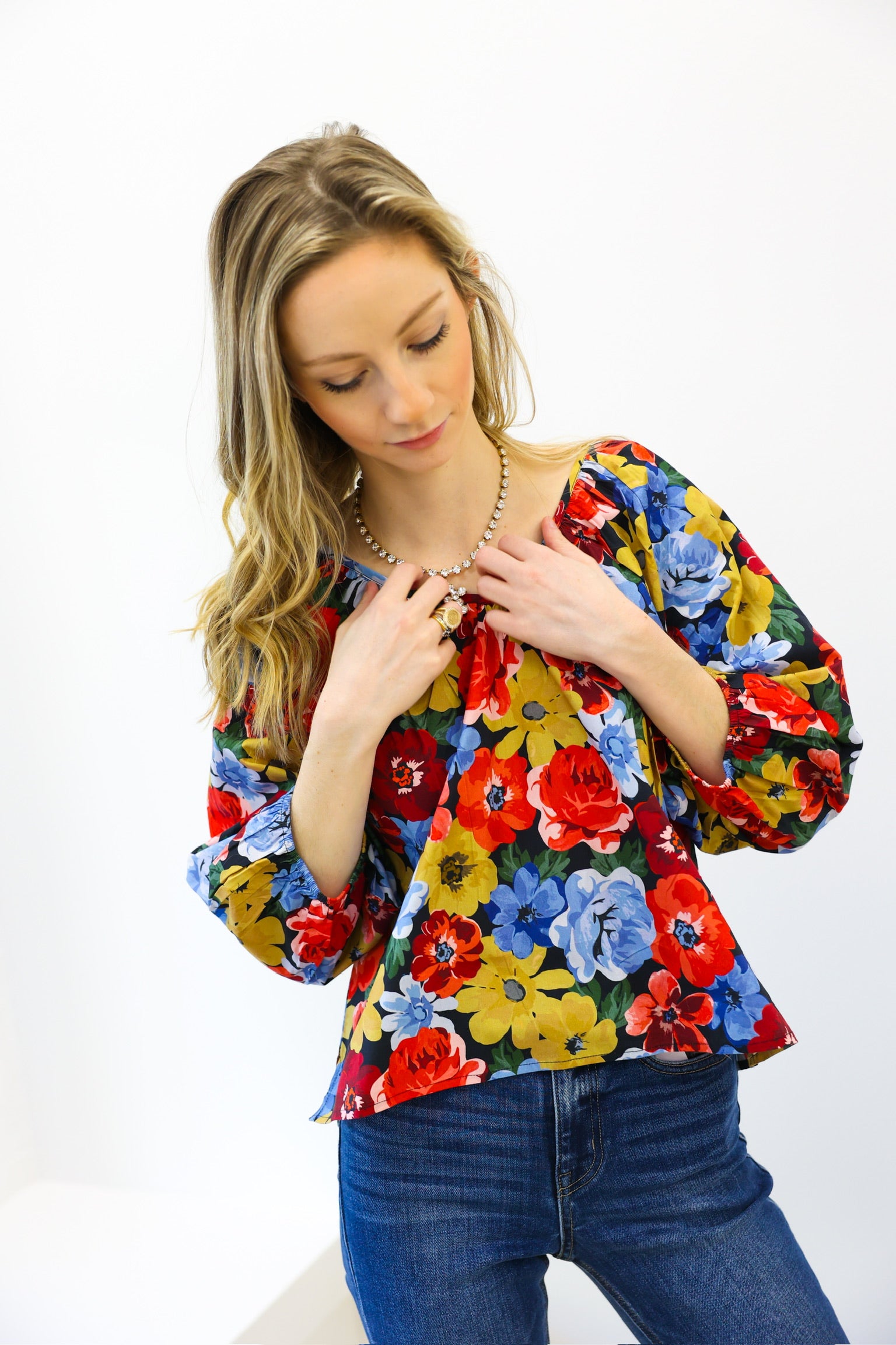 Woman wearing a colorful floral blouse against a white background