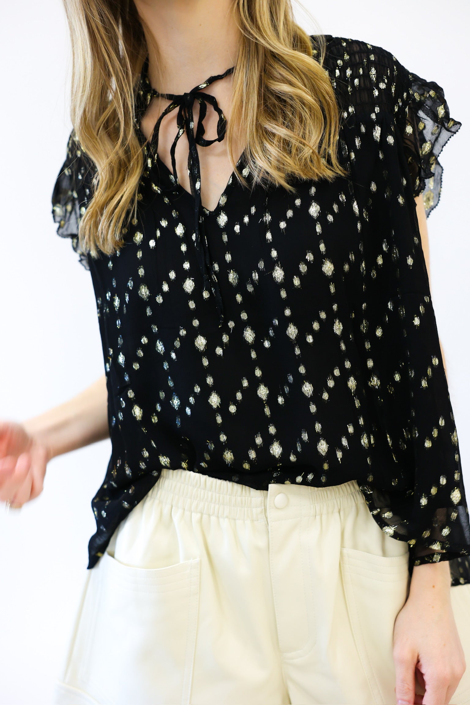 Black floral blouse with white pants on a plain background