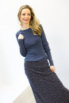 Woman wearing a blue sweater and patterned skirt on a white background