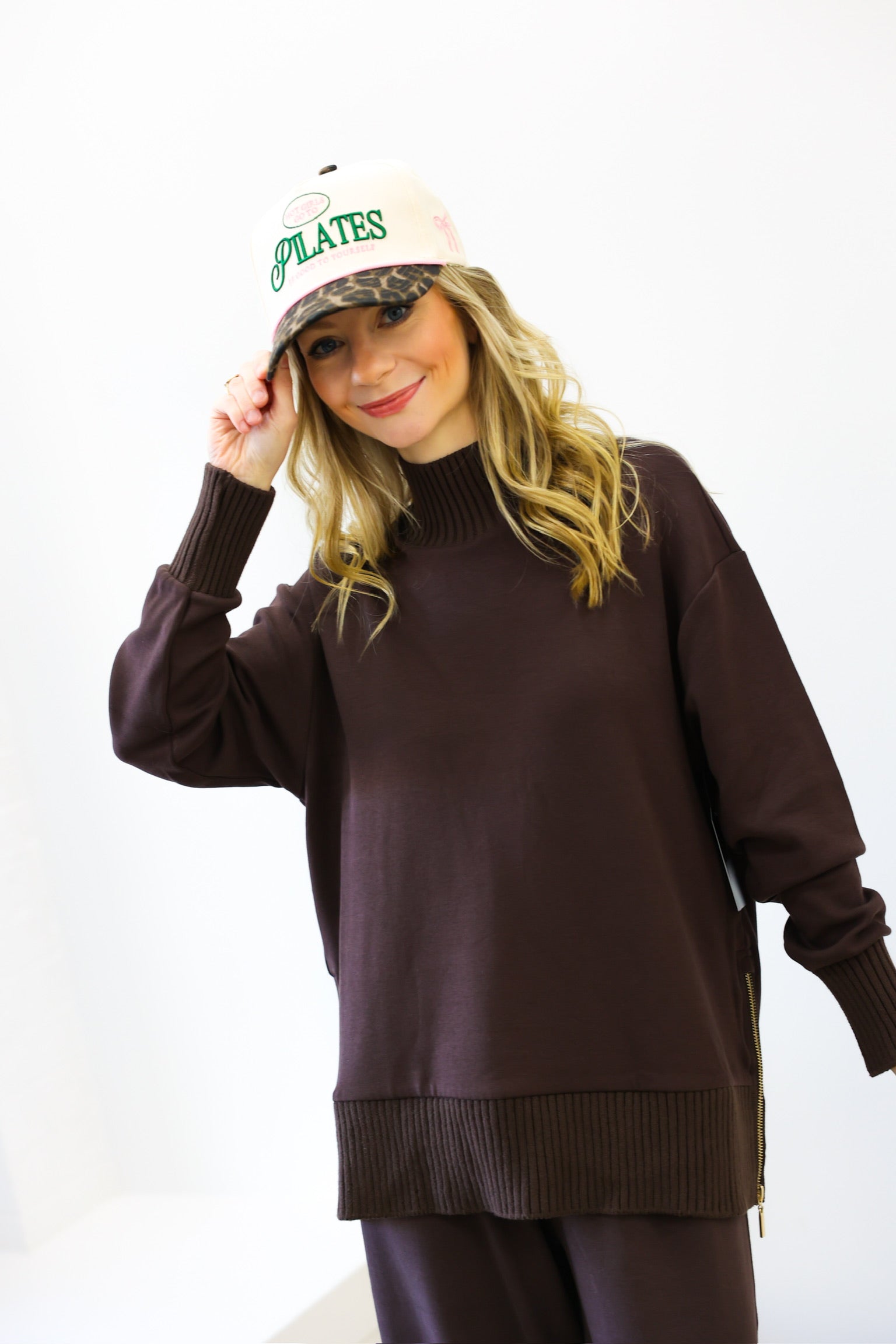Person wearing a brown sweater and white cap with text on a white background