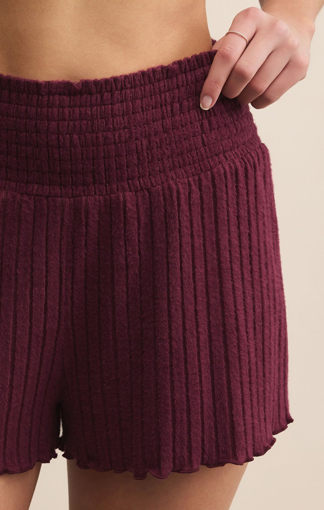 Maroon ribbed shorts worn by a person on a beige background