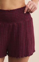 Maroon ribbed shorts worn by a person on a beige background