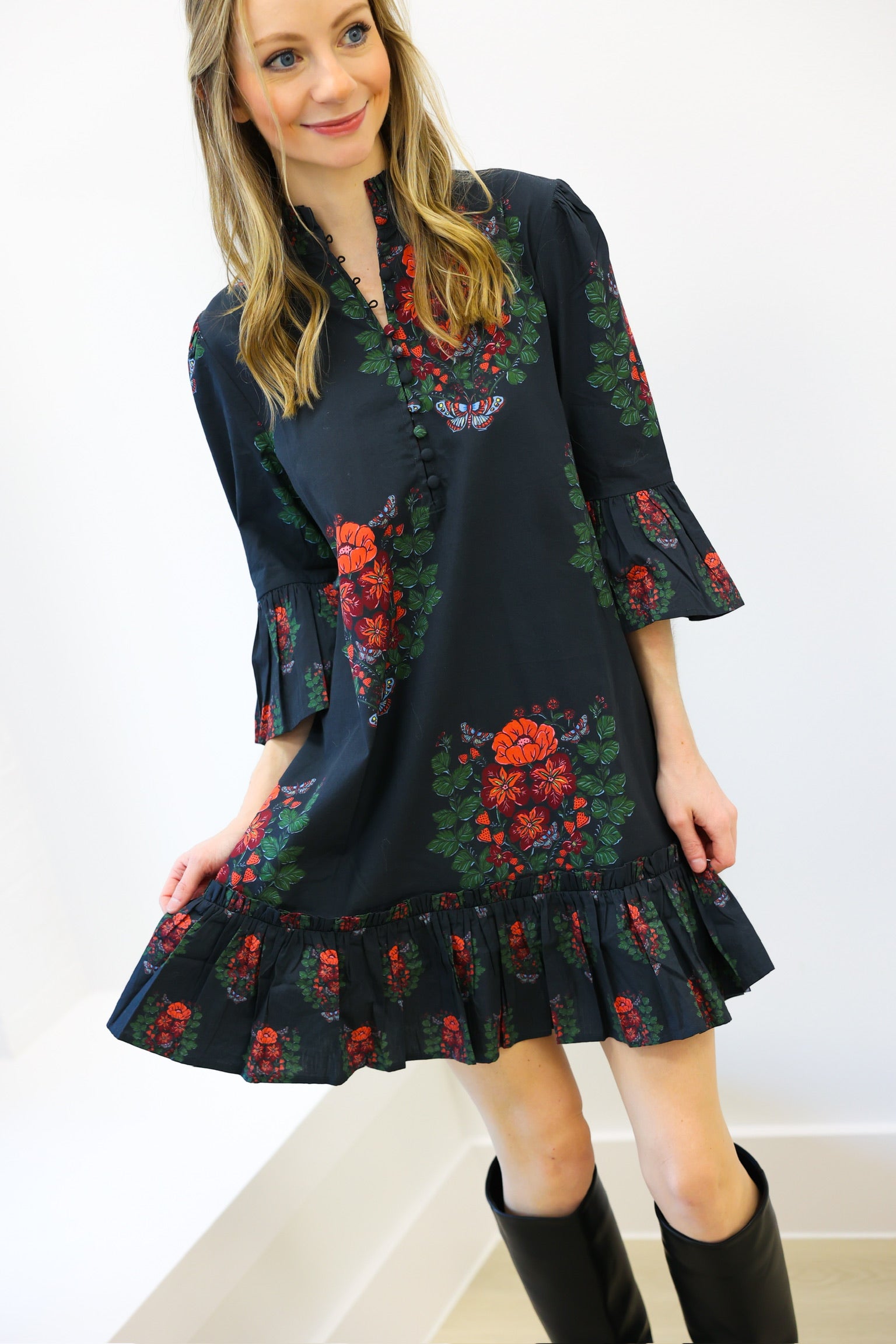 Woman wearing a dark floral dress with bell sleeves against a white background