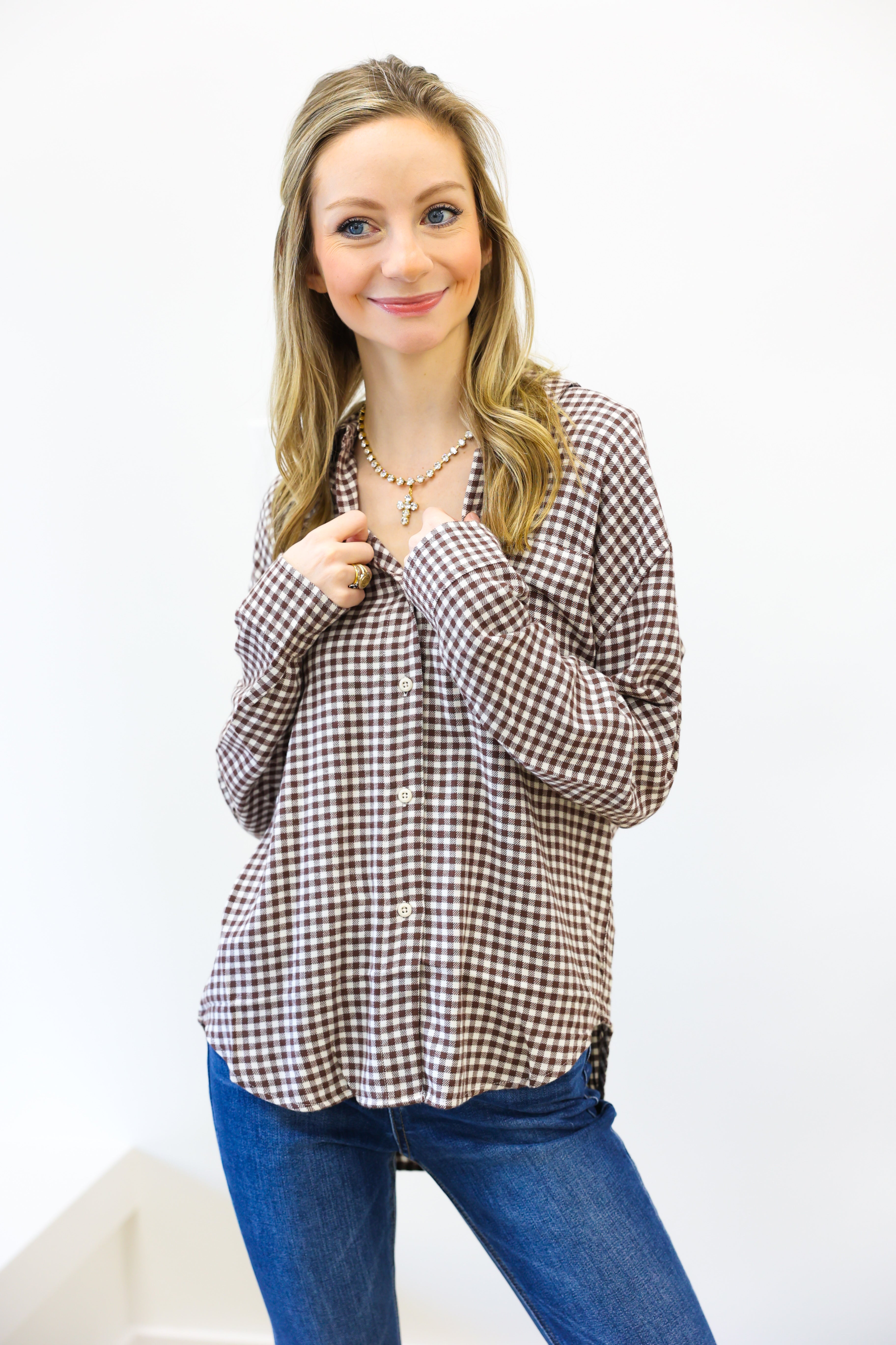 Woman wearing a checkered blouse and blue jeans against a white background