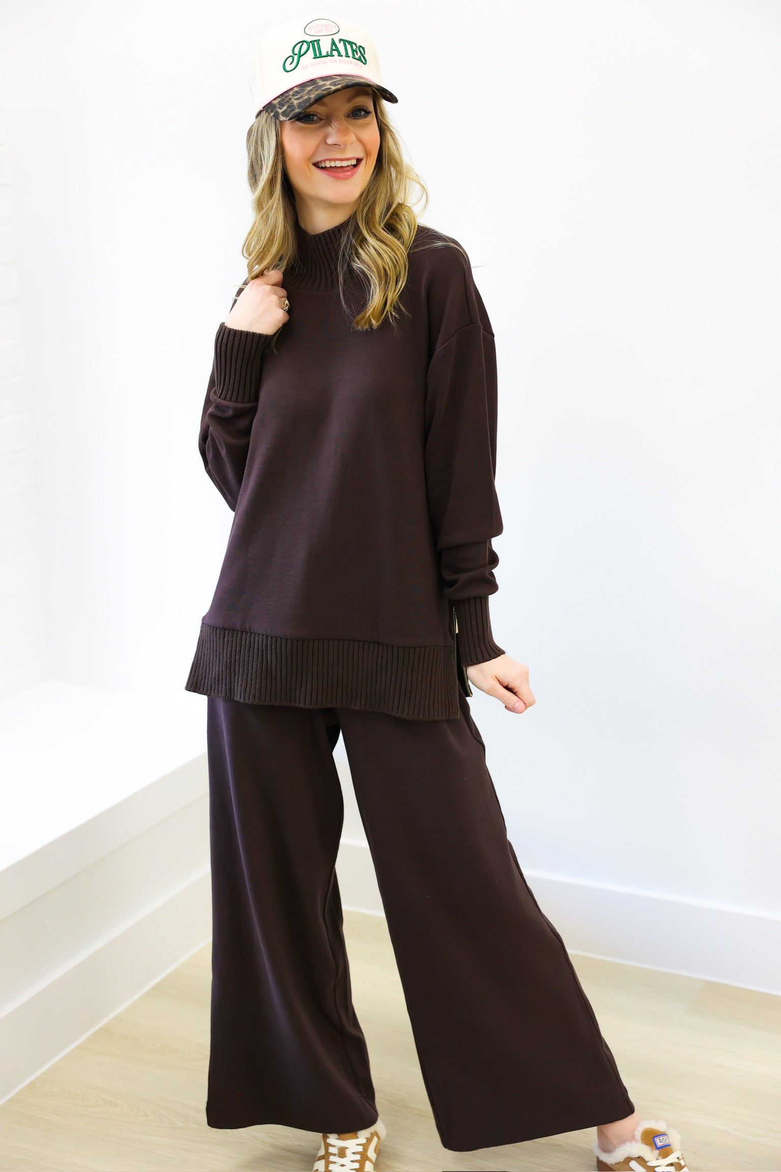 Woman wearing a brown outfit with a white wall background