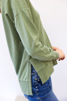 Person wearing a green sweater and blue jeans on a white background