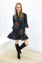 Woman wearing a dark floral dress with black boots on a white background