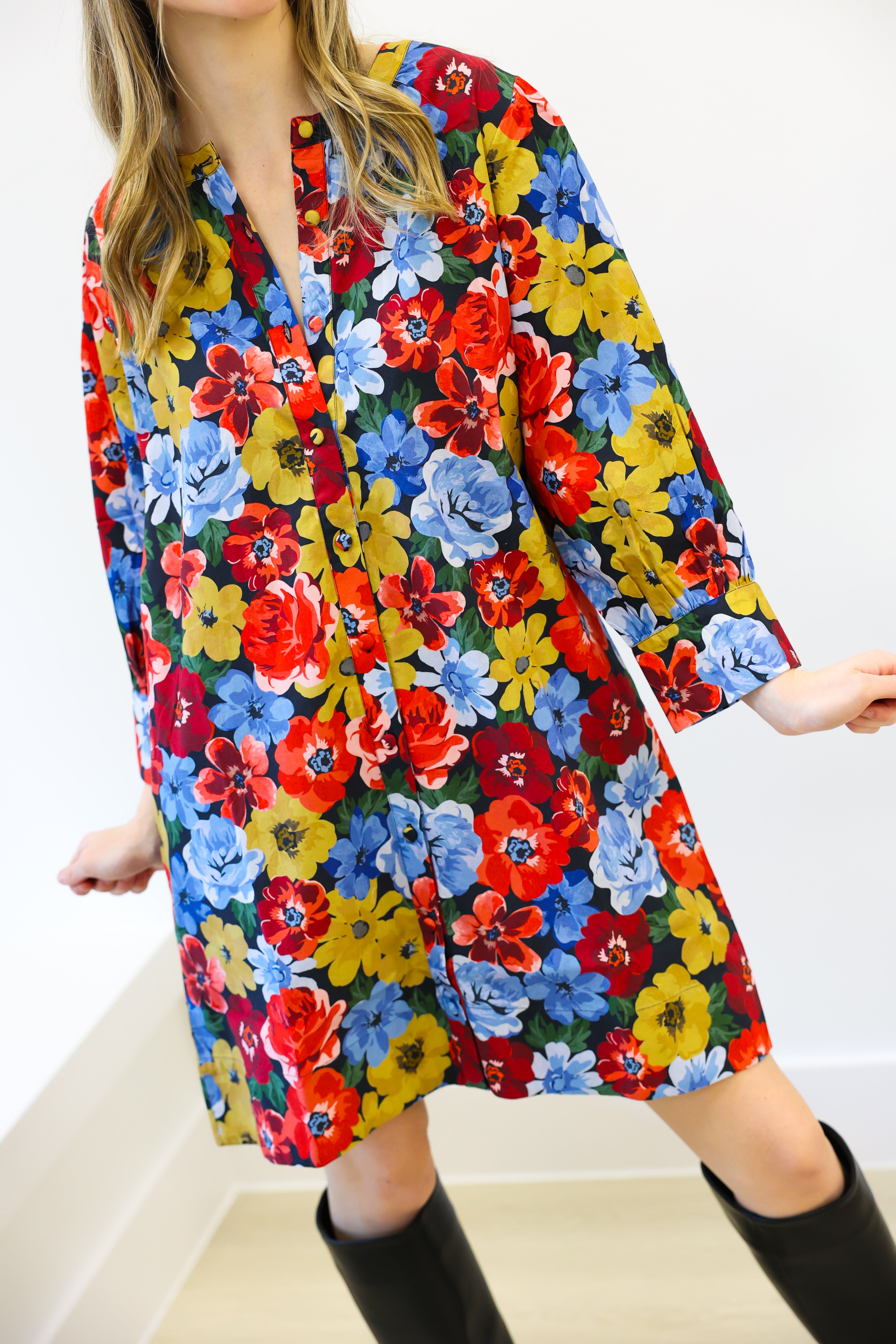 Woman wearing a colorful floral dress with black boots on a white background