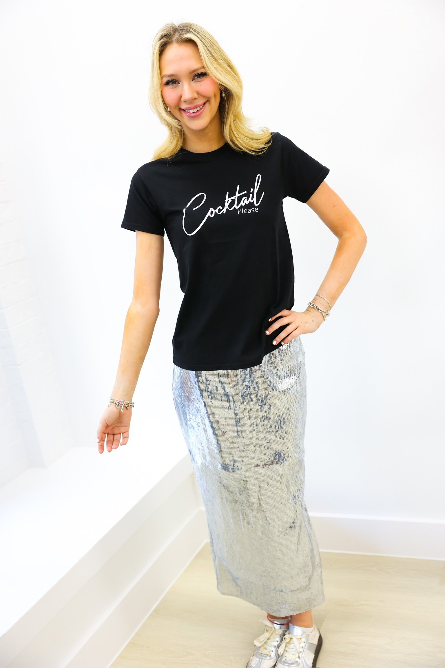 Woman wearing a black t-shirt with 'Cocktail' text and a patterned skirt on a white background