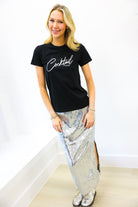 Woman wearing a black t-shirt with 'Cocktail' text and a silver sequin skirt on a white background