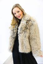 Woman wearing a beige fur coat against a white background