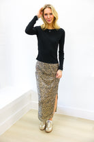 Woman wearing a black top and patterned skirt against a white background