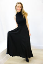 Woman wearing a black sleeveless dress against a white background
