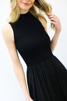 Woman wearing a black sleeveless dress against a white background