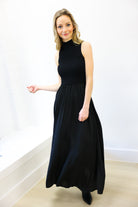 Woman wearing a black sleeveless dress against a white background