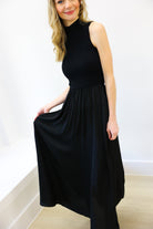 Woman wearing a black sleeveless dress against a white background