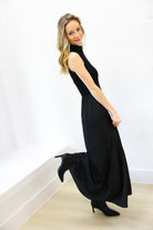Woman wearing a black sleeveless dress and high-heeled shoes on a white background