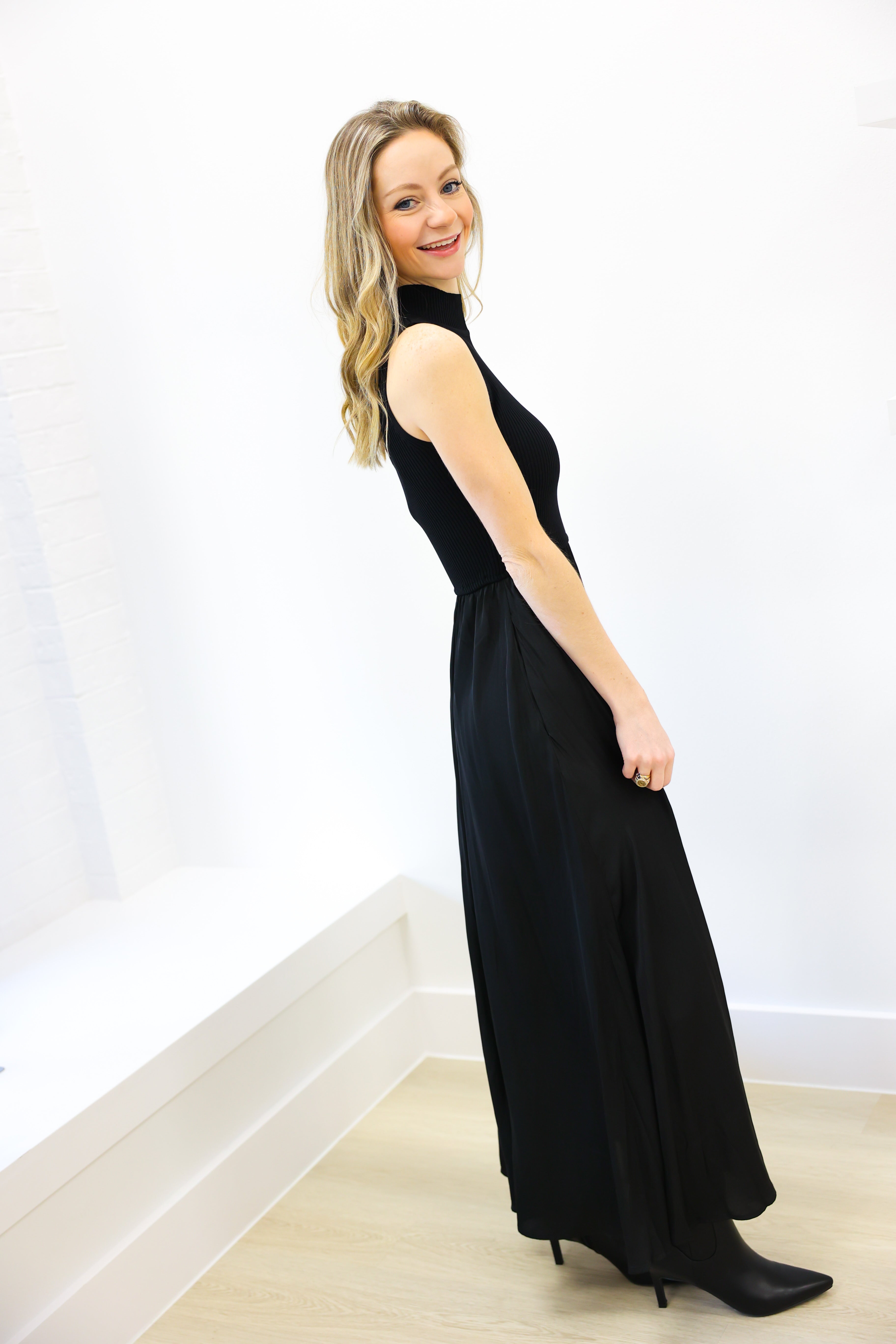 Woman wearing a black sleeveless dress against a white background