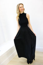 Woman wearing a black sleeveless dress against a white background